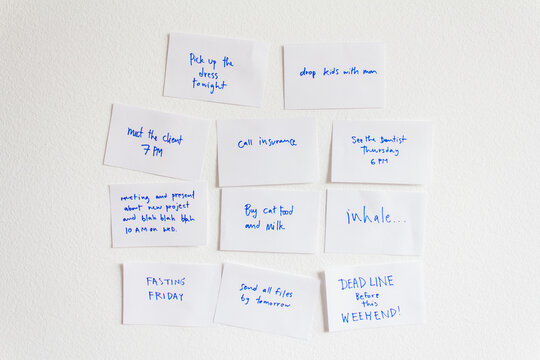 White paper note for reminging written with blue ink on the white wall