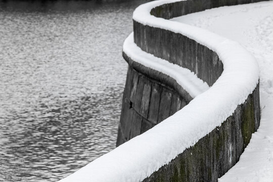 Curved embankment separating water from the bank covered with snow