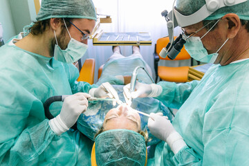 Two dentists with a woman patient during a implant intervention