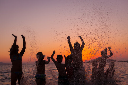 Group og Children Playing with Water at Sunset