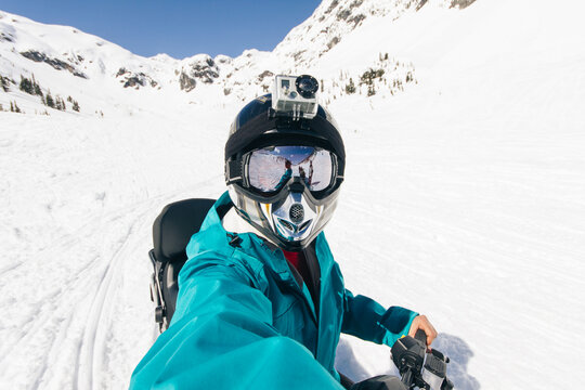 Young man taking a photo of himself riding a snowmobile on the snow in winter