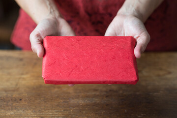 Hands with Christmas gift in red wrapping paper