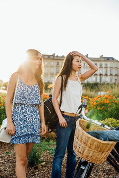 Two Feamale Friends Stand Near a Garden
