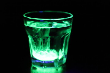 A Glass with a Glowing Green and Yellow Liquid Swirling Around Inside