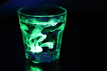 A Glass with a Glowing Green and Yellow Liquid Swirling Around Inside