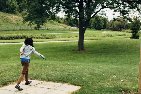 African American girl throwing a disc at a disc golf outing