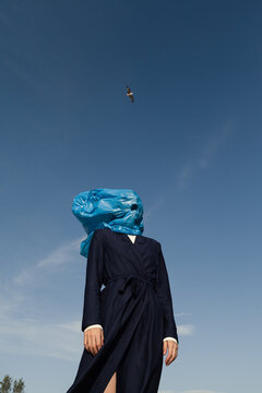 woman with blue trash bag covering her face
