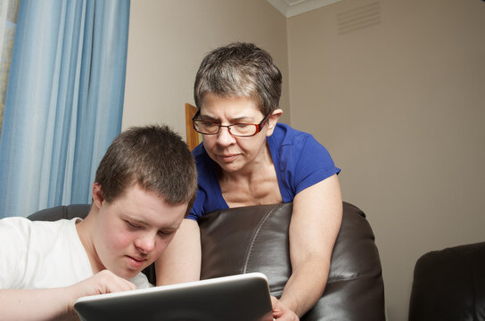 Mother assisting teenager to use a tablet computer