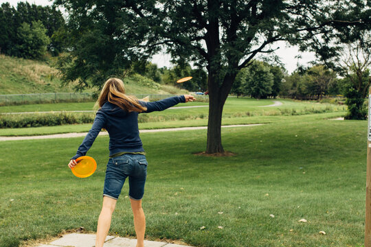 Female throwing a disc at a disc golf tournament