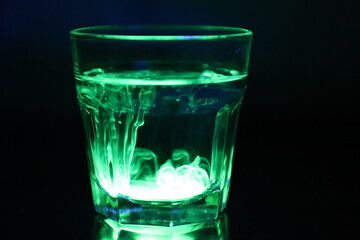 A Glass with a Glowing Green and Yellow Liquid Swirling Around Inside