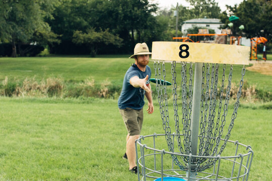 Man throwing a disk at a basket target catcher