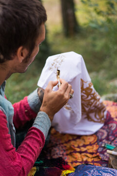 Young hippie man drawing some batik in nature