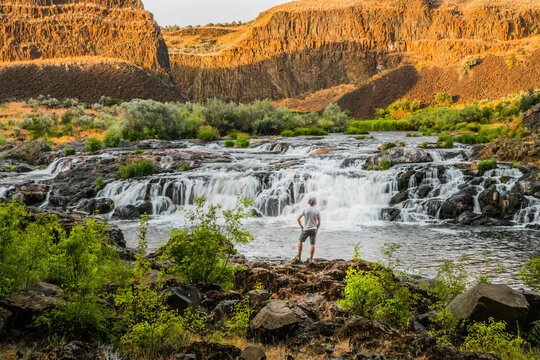 Man Looking Upon Oasis, Waterfall And River Flowing Through Dese