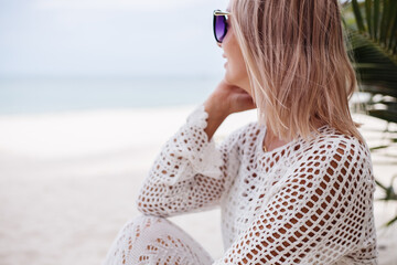 Woman in knitted white clothes on beach 