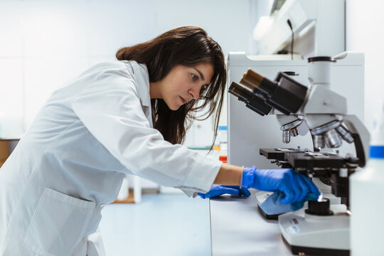Young Biologist Cleaning the Microscope Lens