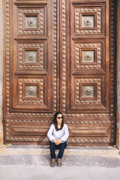 Woman in front of a large wooden door