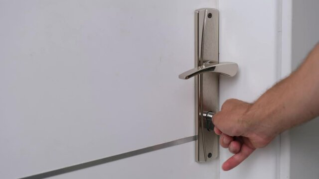The man opens the door of the room with the key.