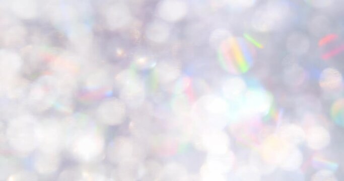 Luxurious soft white background with glittering floating particles and a shiny rainbow reflection.