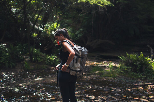 Woman buckling her backpack in the forest