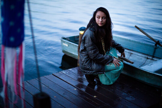 Young girl waits patiently on the dock, holding her row boat