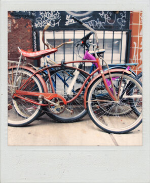 Old polaroid photograph of bicycles locked together on a city sidewalk