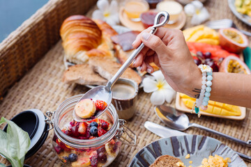 Woman having tropical healthy breakfast at villa on floating table  