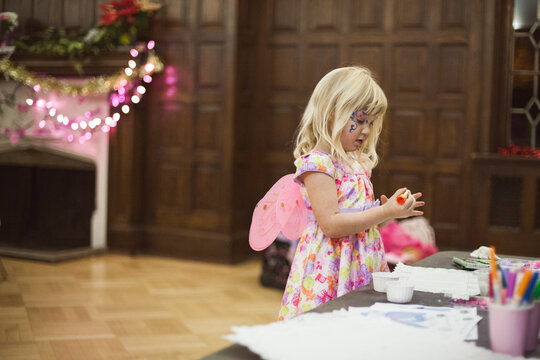 Little girl with fairy wings at colouring table.