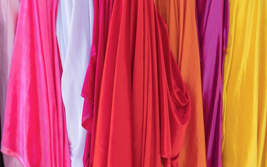 A selection of colorful clothing as a background, a variety of colorful rainbow fabrics, multi-colored curtain fabric backgrounds, a colorful blank sheet silk texture.