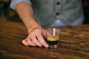 Barista serves dark espresso coffee