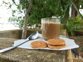 A cup of milk chocolate on a white background with crispy cake in a city park.