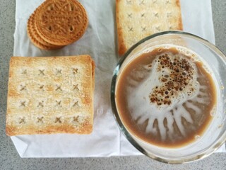 A cup of milk chocolate on a white background with crispy cake in a city park.