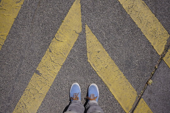 Blue sneakers between street markings, footsie, personal perspective
