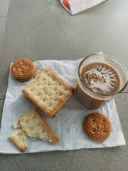 A cup of milk chocolate on a white background with crispy cake in a city park.