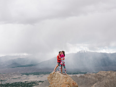 Couple kissing on top of mountain with rain in background