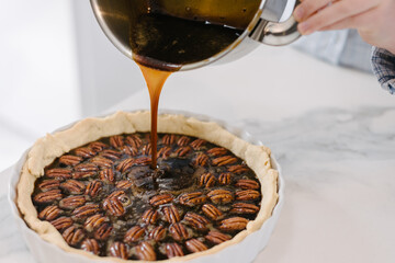 carefully pouring syrup in pecan pie, trying not to displace the carefully laid pecans