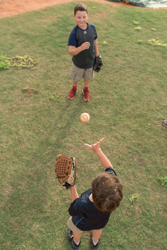 Two Brothers Play Catch On A Baseball Field