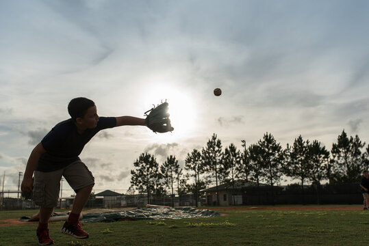 A Boy Catches A Ball At Sunset