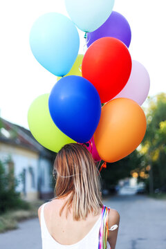 Woman holding colorful balloons from the back
