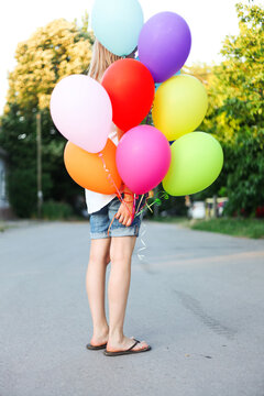 Woman holding colorful balloons in the street