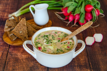 Summer cold soup okroshka.  Traditional Russian soup okroshka with kvass, radish, cucumbers, eggs, sausage, green onions and sour cream. 