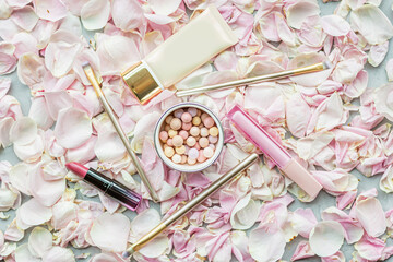 Cosmetic products on pink rose petals. Flat lay, top view.