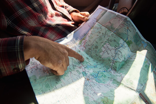 Man's hand pointing at a map of California in the car.