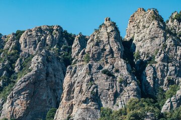 Ridge of brown rocks covered with greenery against a blue sky