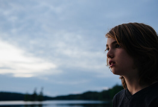 Boy looks out at the water at dusk