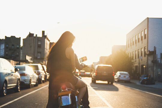 Couple riding into city sunset on motorcycle.