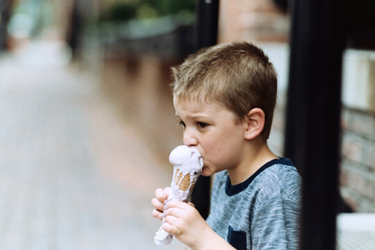 Young boy taking a bite of quickly melting ice cream