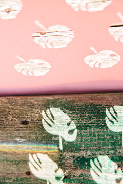 Half palm tree pattern stencil and half casted shadow on wooden background