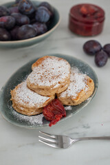 home made blini pancakes with plums on a table