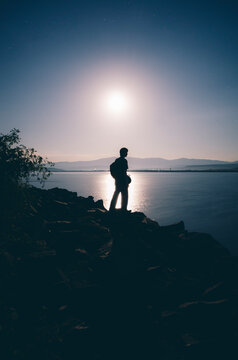 Man on lake edge with moon shining over lake