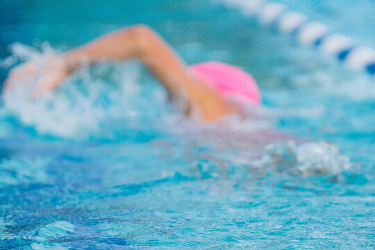 Blurred image of young woman swimming away